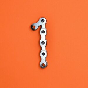 Metal chain forming the number one on an orange background, ideal for design concepts.
